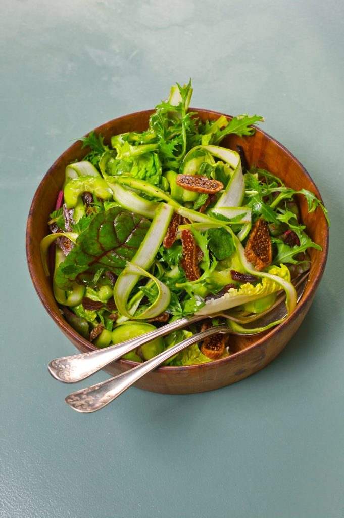 a wooden bowl filled with a salad and two spoons